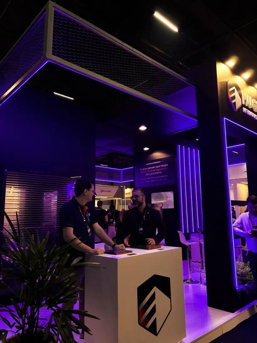 Estande da Huge Networks em evento do setor, com equipe atendendo visitantes