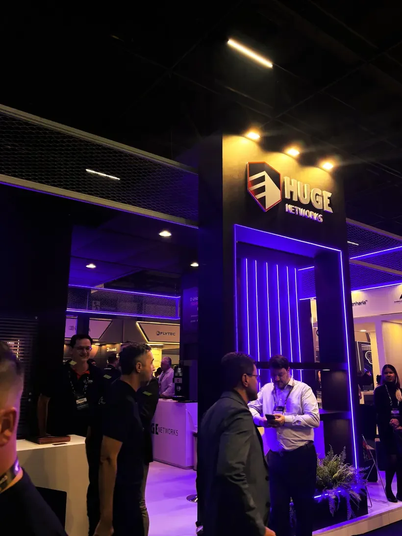 Logo da Huge Networks iluminado no estande em feira de tecnologia